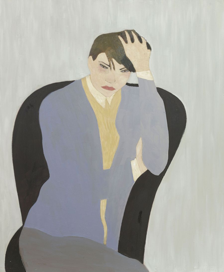 person sitting on chair holding their head.