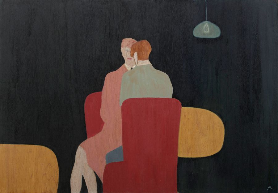 two people sitting on red chairs against a dark background.